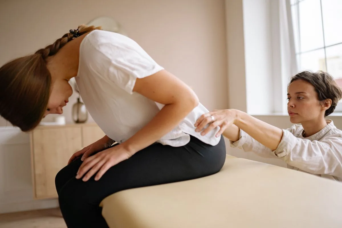 Physical therapist assessing a patient’s lower back and spine